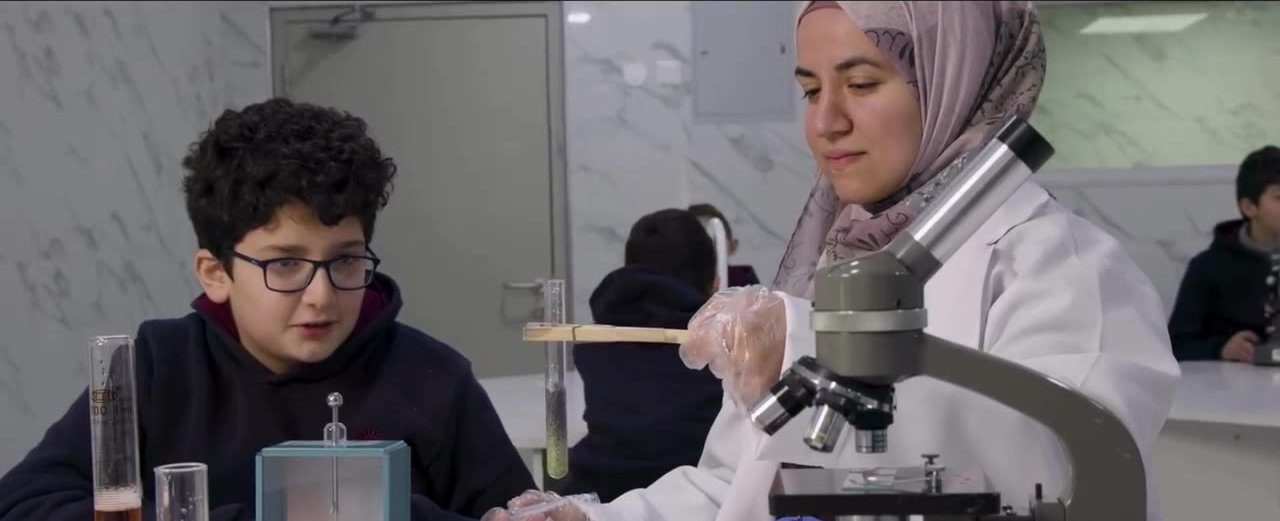 طالب يعمل مع معلّمة على المجهر